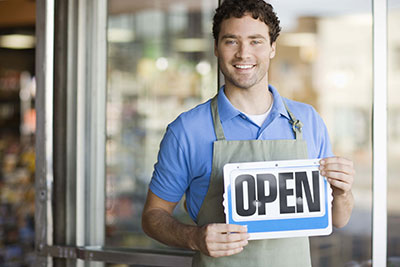 Small business owner holding an Open sign