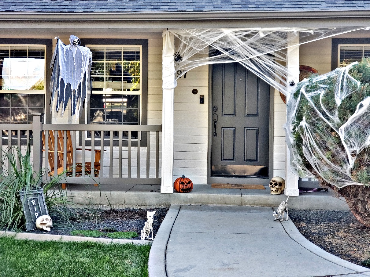 Front of a house decorated for Halloween with  pumpkins, skulls, and spider webs