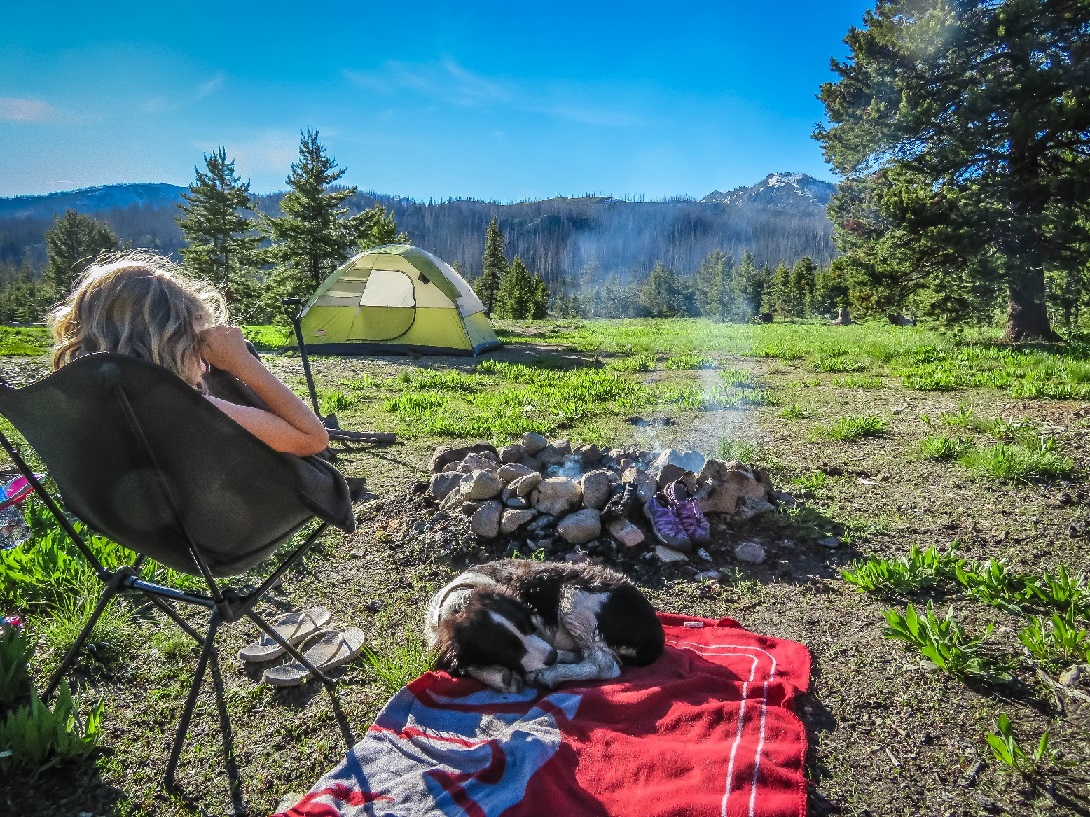 Child and dog sitting around campfire in the mountains.  Protecting your camp gear.  Home Insurance Coverage - The Miller Insurance Agency Everett Washington