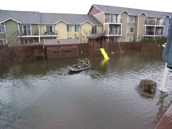 Man kayaking in flooded back yard